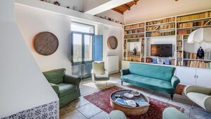 Un salon comprenant un canapé, des fauteuils, une table basse, une bibliothèque et un téléviseur.