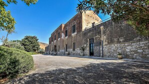 Un bâtiment doté d’une façade en pierre, de grandes fenêtres et d’un espace d’entrée pavé.