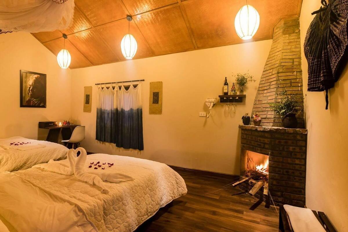 Una habitación acogedora con dos camas, una chimenea y un escritorio con lámpara.