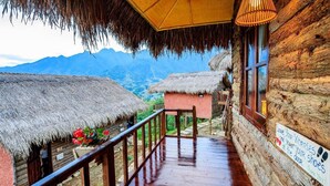 A wooden cabin with a thatched roof, a wooden deck, and a sign with footprints and a heart. - Sapa Rosie House - Mountain Retreat (Sa Pa)