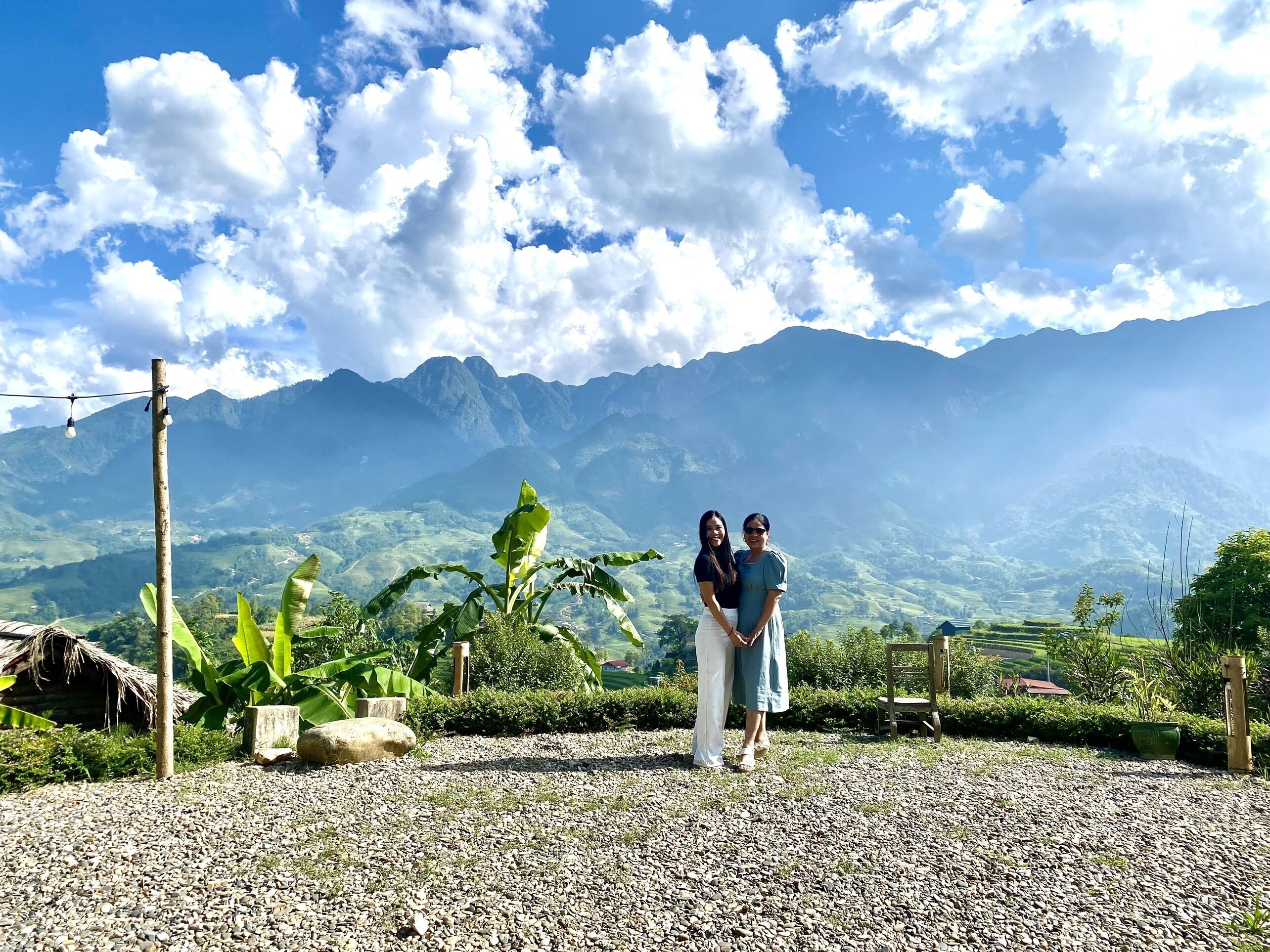 A couple standing in a garden with a mountainous backdrop.