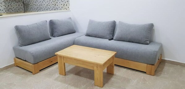 A grey sectional sofa with wooden legs and a wooden coffee table in front.