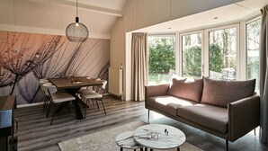 Un salon moderne avec un coin repas, de grandes fenêtres et une vue sur l’extérieur.