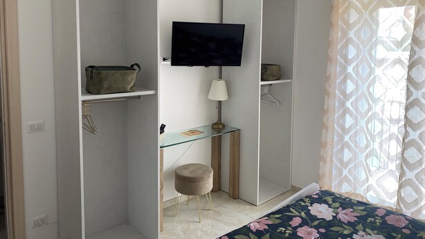 Ein Schlafzimmer mit Bett, Fernseher, Glastisch und Kleiderschrank.