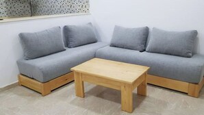 A grey sectional sofa with wooden legs and a wooden coffee table in front. - 4:ain el Turck Superbe Appartement en Résidence (Aïn El Turk)
