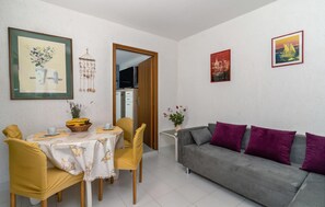 Cozy living space with a dining area and seating area, featuring a table, chairs, and a sofa with a side table.