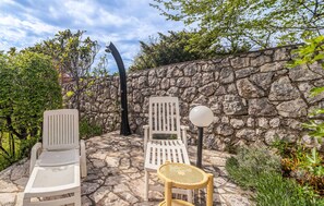 Relax in a serene outdoor space with two lounge chairs and a small table amidst lush greenery.