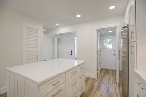 A modern kitchen with white cabinetry, a large island, and a refrigerator. - 1625 Port Villas: Water Views, Dock and Steps to the Salty Dog - Free Bikes (Hilton Head Island)