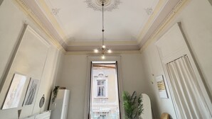 Camera d'albergo con un letto, una scrivania, una sedia, una TV e un balcone con vista sull'edificio.