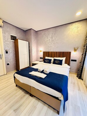 A hotel room with a bed, a wardrobe, and a nightstand. - Taxim Alyon Suite Hotel (Istanbul)
