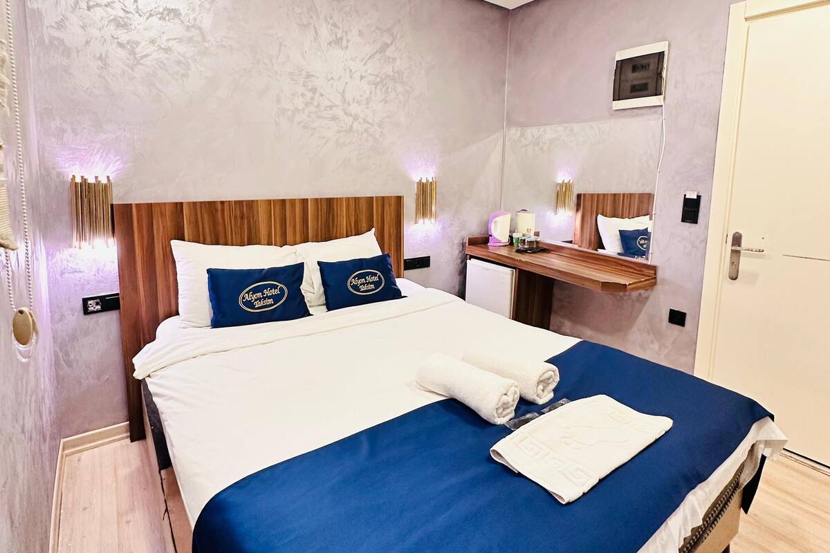 Une chambre d’hôtel avec un grand lit, une tête de lit en bois, une table de chevet, un miroir et une porte.
