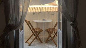 An open balcony with a table and chairs, a white umbrella, and a view of buildings with a tiled roof. - Nice F3 100 m from the Place de la Comédie (Montpellier)