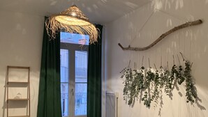 A bedroom with a bed, a hanging light fixture, a window with curtains, and a wall-mounted plant. - Nice F3 100 m from the Place de la Comédie (Montpellier)