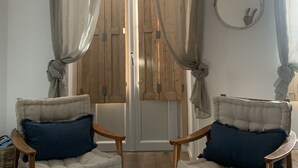 A room with two upholstered chairs, a wooden door with glass panels, and a wall-mounted mirror. - Nice F3 100 m from the Place de la Comédie (Montpellier)