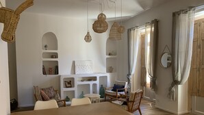 A dining area with a wooden table and chairs, a white shelving unit with decorative items, and hanging wicker lamps. - Nice F3 100 m from the Place de la Comédie (Montpellier)