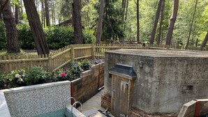 A swimming pool with a wooden deck, surrounded by a wooden fence and a brick wall.