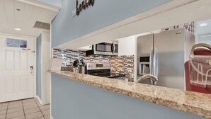 Una cocina moderna con encimera de granito, electrodomésticos de acero inoxidable y salpicadero con diseño de playa.