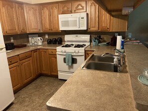 Una cucina con mobili in legno, piano cottura bianco, lavello e forno a microonde.