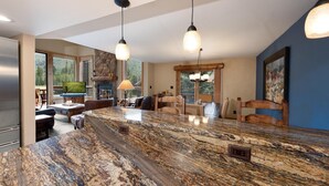 A spacious kitchen with a granite island, pendant lighting, and a stone fireplace. - Corner Cascade Village Condo - Largest deck - Fire Pit - Views - Heated Pool (Durango)