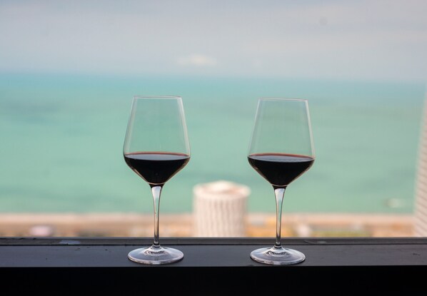 Two wine glasses on a windowsill with a view of the ocean. - Season Suite Apart-Hotel (Batumi)