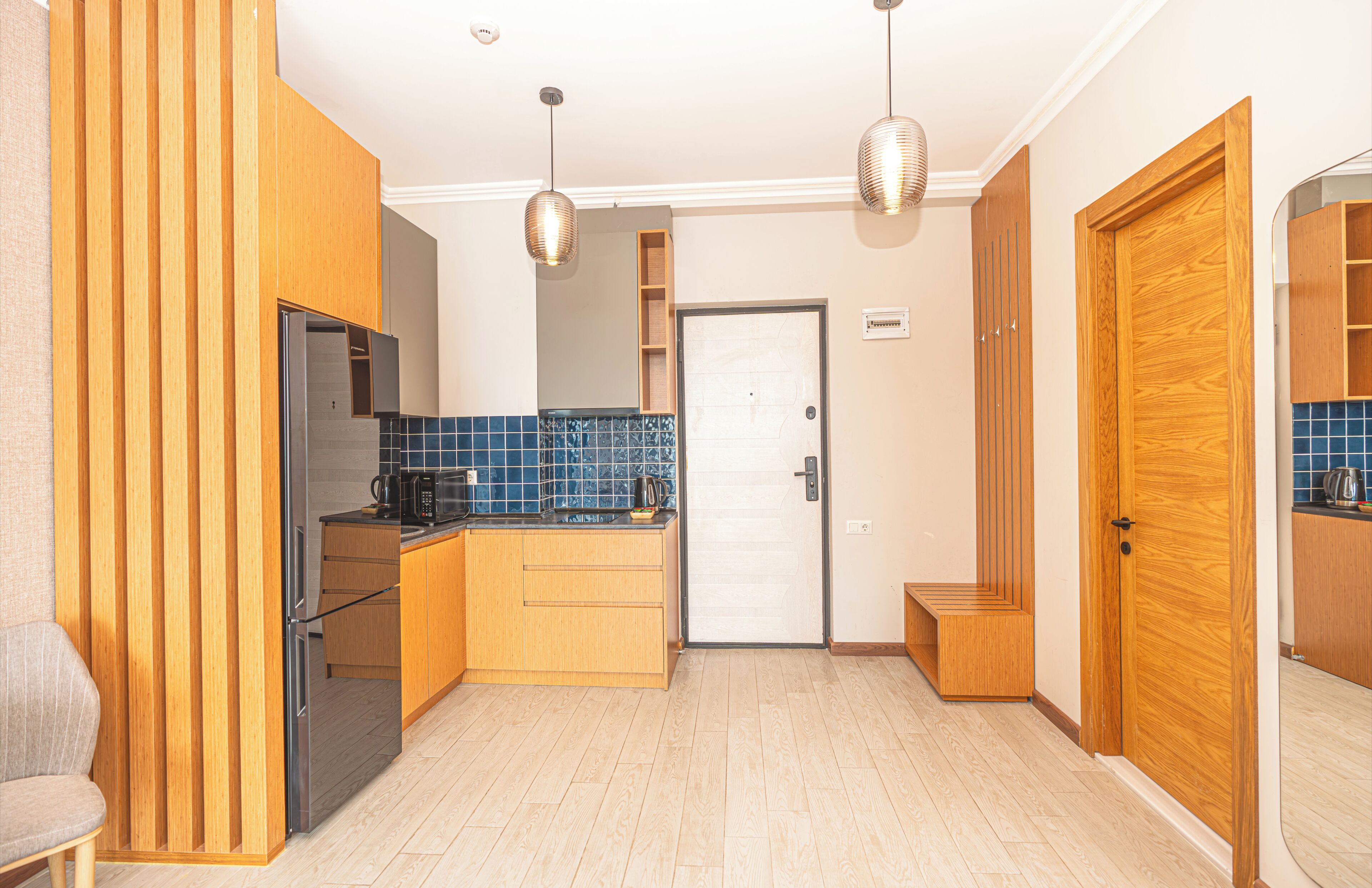 A modern kitchen with wooden cabinets, a built-in oven, and a tiled backsplash.