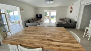 A spacious living area with a large wooden dining table, two sofas, and a television. - ¡nuevo! Villa Blanca. Besado por el sol y el Océano (Callao Salvaje)