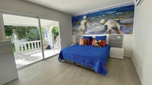 A bedroom with a large bed, a painting on the wall, and a sliding glass door leading to an outdoor area. - ¡nuevo! Villa Blanca. Besado por el sol y el Océano (Callao Salvaje)