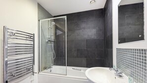 Ein modernes Badezimmer mit einer begehbaren Glasdusche, einer weißen Badewanne und einem Waschbecken mit Spiegel darüber.