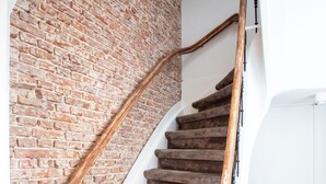 Eine Treppe mit einer Backsteinwand auf der einen Seite und einer weißen Wand auf der anderen, mit einem Holzgeländer.