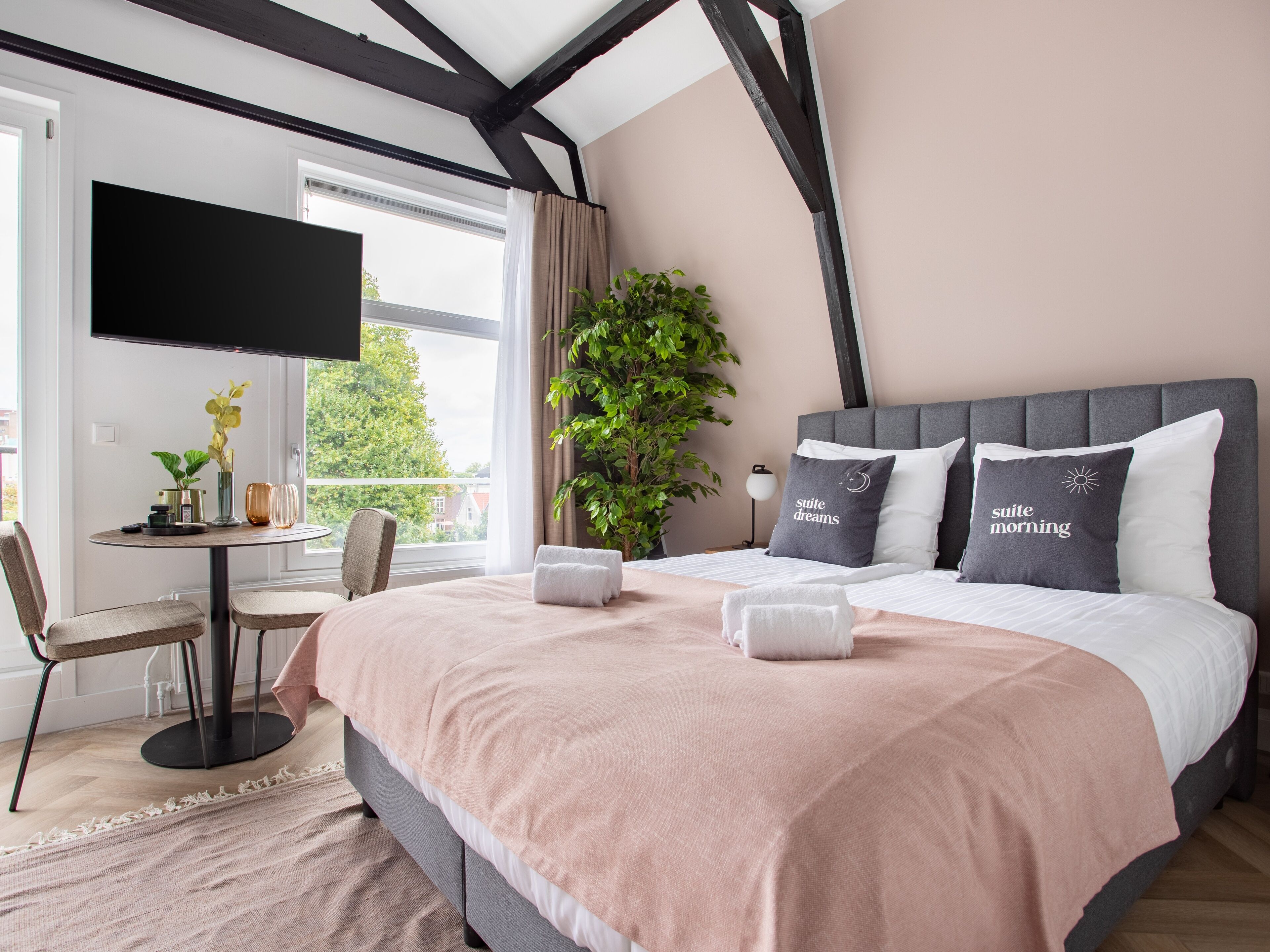 A modern bedroom with a large bed, a desk, and a TV.
