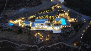 Luchtbeeld van een resort met meerdere gebouwen, een zwembad en verlichte paden.