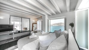 Een moderne hotelkamer met een groot bed, een televisie en uitzicht op zee.