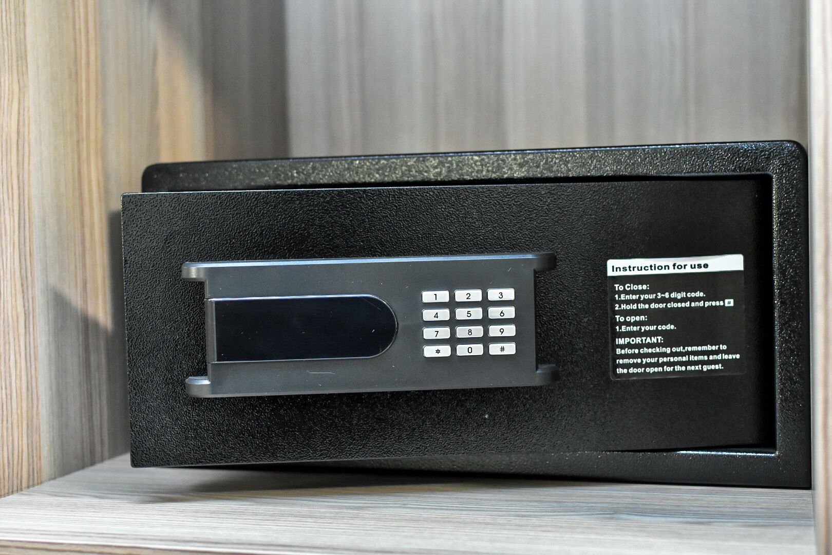 Een zwarte kluis met een keypad en gebruiksaanwijzing.