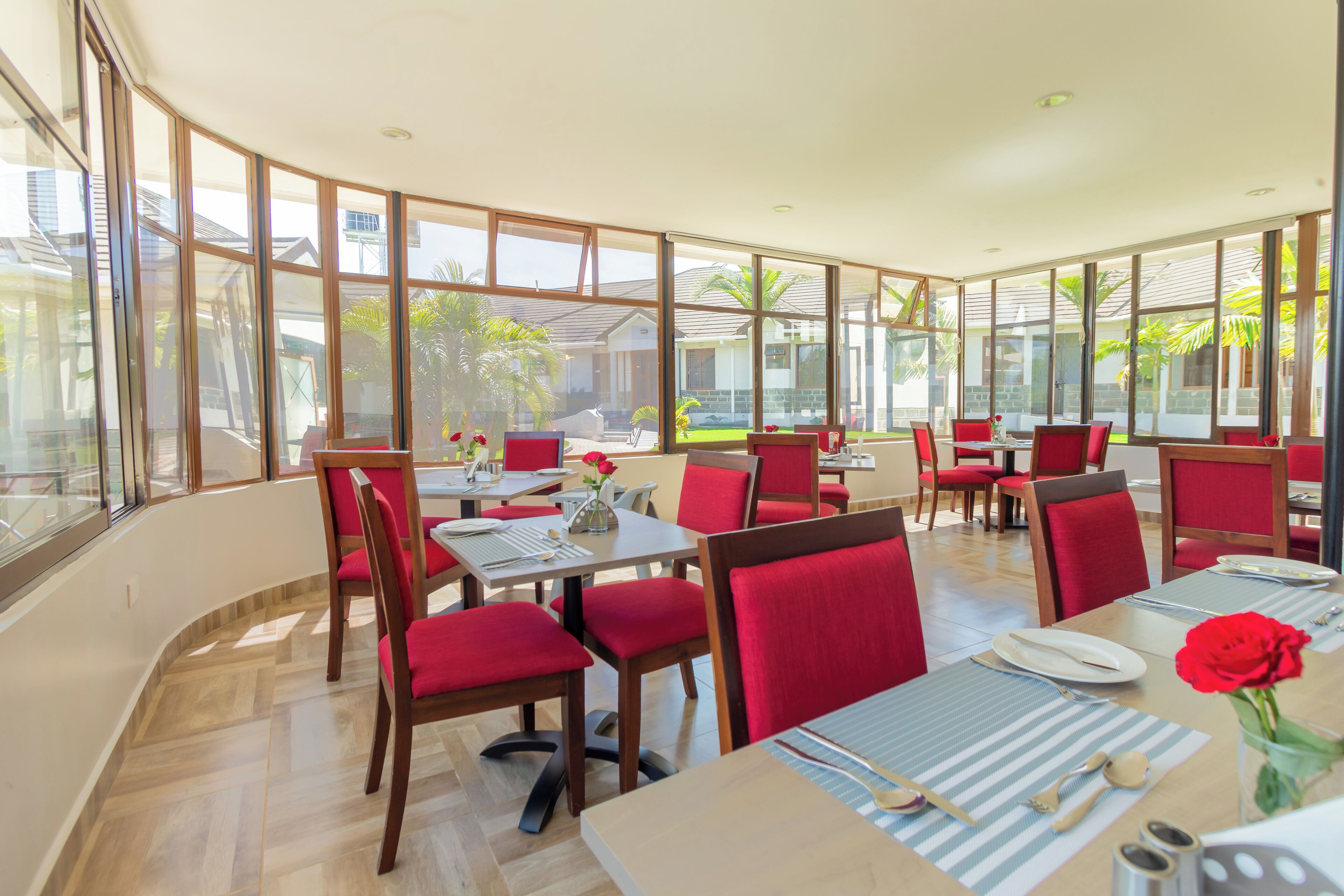 Un restaurante con sillas y mesas rojas, ventanas grandes y vistas al exterior.