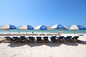 Ein Strand mit Reihen von Liegestühlen und Sonnenschirmen.