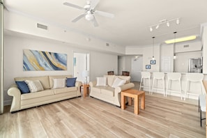 A spacious living area with a sofa, coffee table, and a kitchen in the background.
