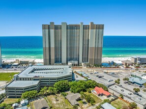 A high-rise hotel with multiple floors, a parking garage, and a beach view.