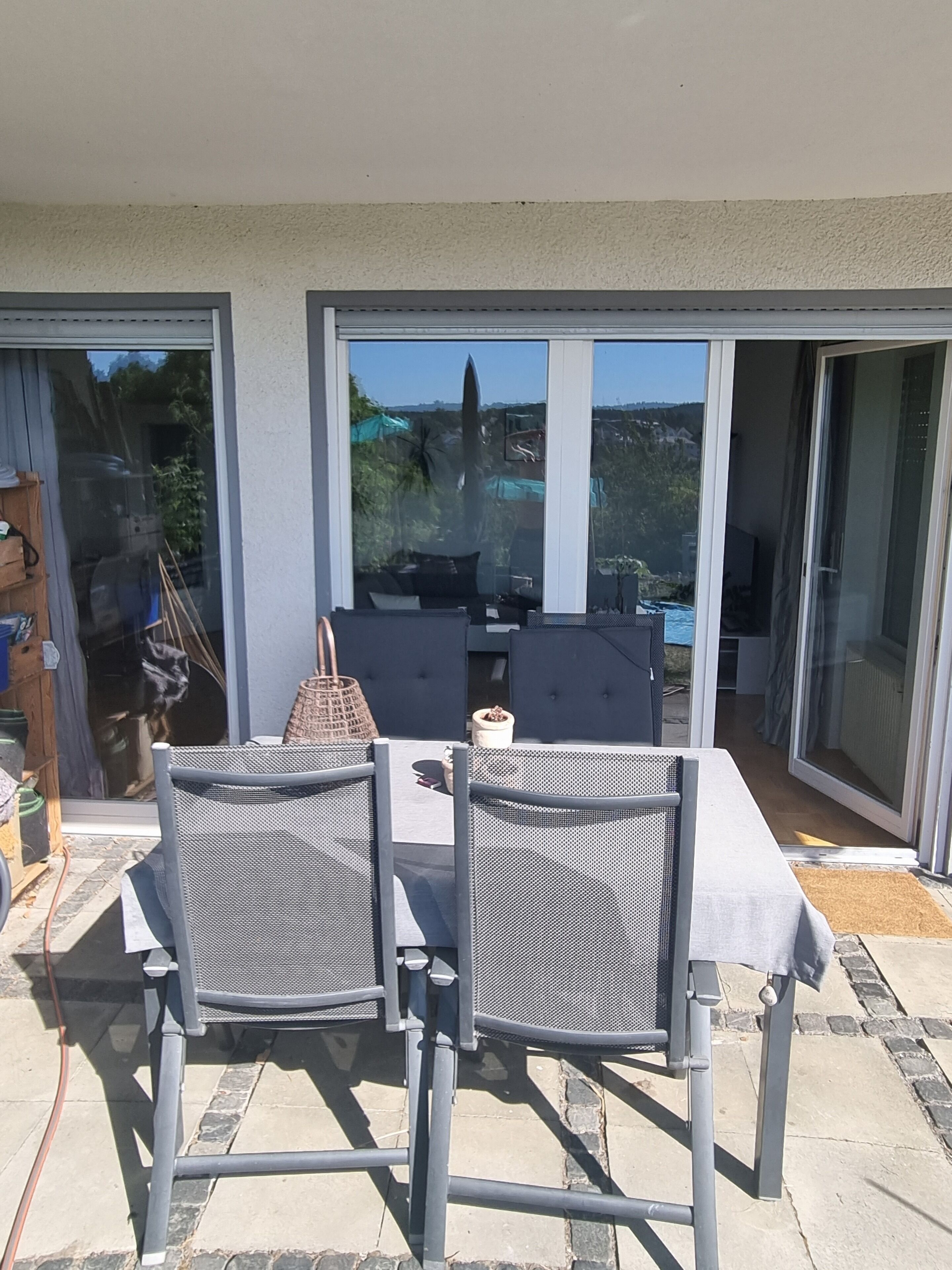 An outdoor patio with a table and chairs, a grill, and a view of the surrounding area.