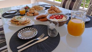 A breakfast table with various pastries, fruits, and a pitcher of orange juice. - Blue Sky Villa in Crete (Hersonissos)