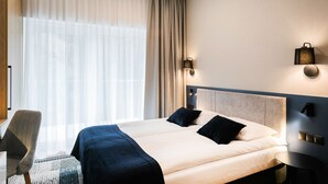 A hotel room with a large bed, a chair, a small table, and a window with sheer curtains. - Hotel Vesper House (Gdansk)