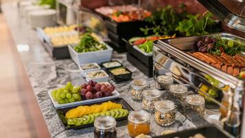 A buffet with various food items including fruits, vegetables, and meats.
