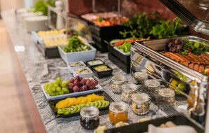 A buffet with various food items including fruits, vegetables, and meats.