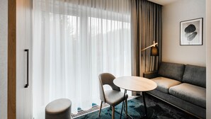 A modern hotel room with a sofa, a round table, and a chair. - Hotel Vesper House (Gdansk)