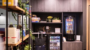 A compact hotel room with a minibar, a refrigerator stocked with beverages, and a small seating area with a sofa and a table. - Hotel Vesper House (Gdansk)