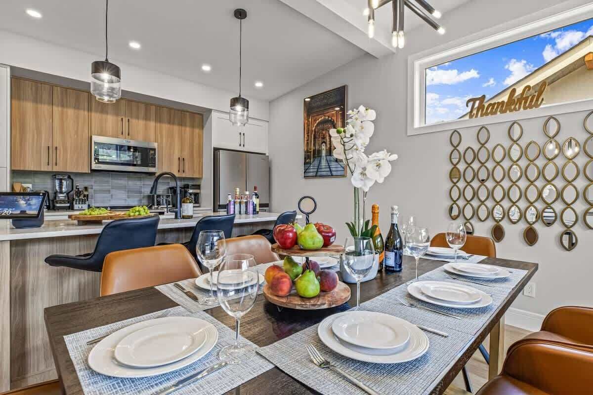 A modern kitchen with wooden cabinets, stainless steel appliances, and a dining area set for a meal.