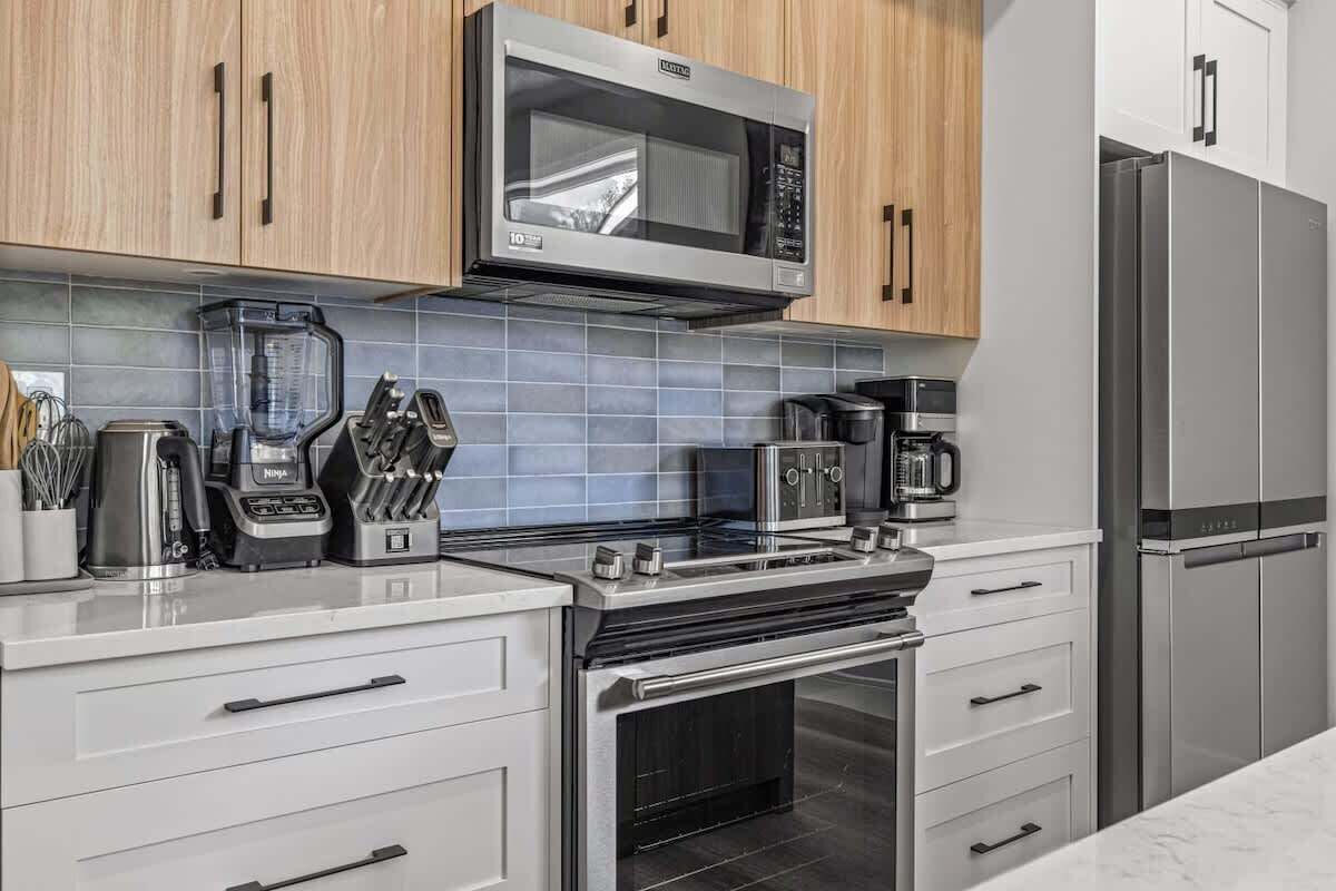Una cocina moderna con electrodomésticos de acero inoxidable, microondas, cafetera y licuadora.
