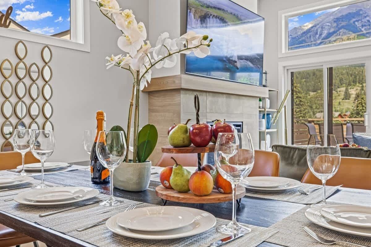 A dining table set with plates, wine glasses, and a fruit centerpiece.