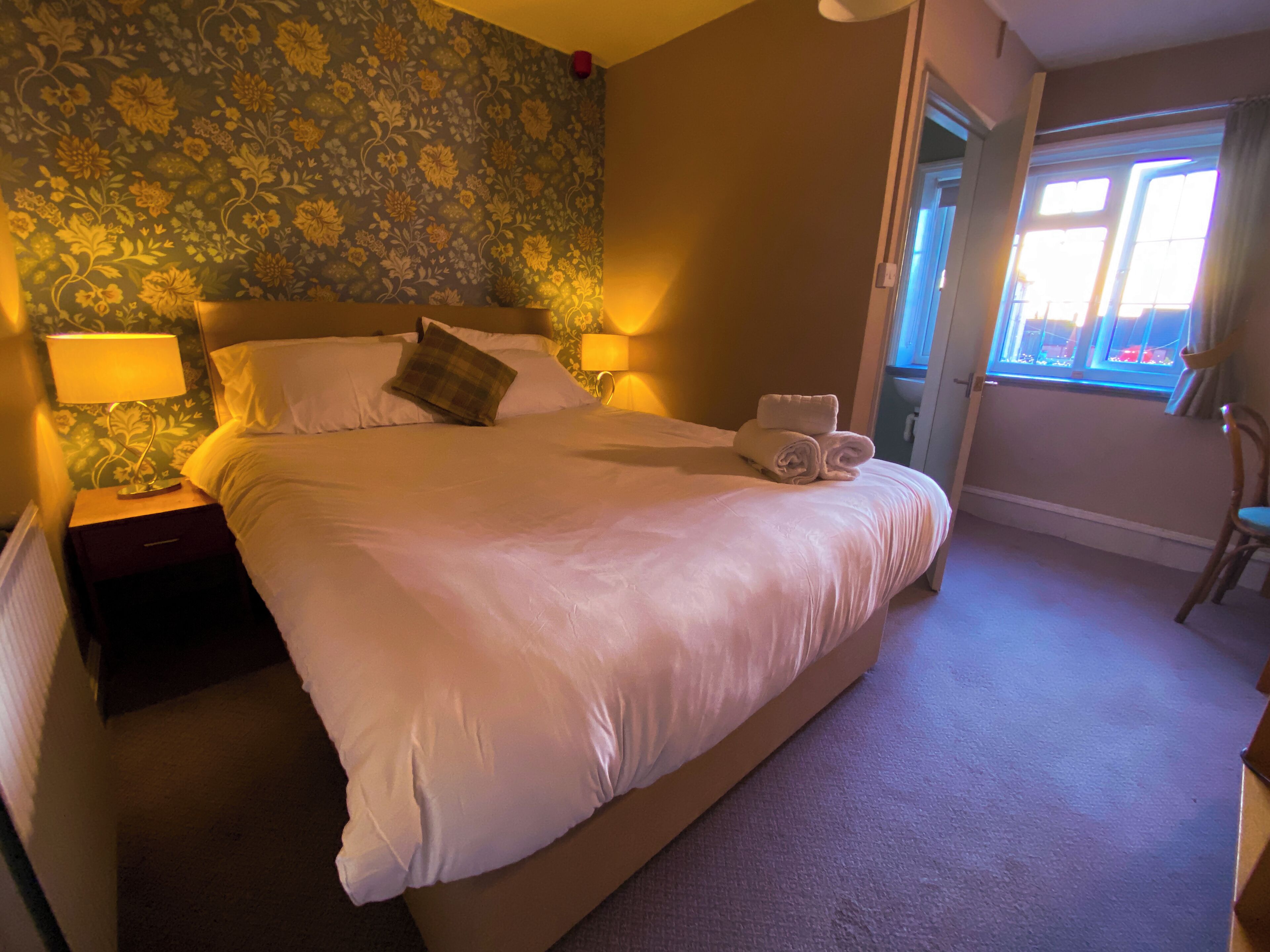 A neatly made bed with white linens, a headboard, and two bedside lamps.