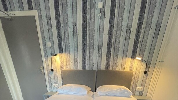 Ein Doppelbett mit Kopfteil, zwei Nachttische und eine Wand mit vertikalen Holzbrettern.