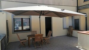 An outdoor patio with a table and chairs, a large umbrella, and a view of a building with windows. - Very central and airy apartment in Palau (Palau)